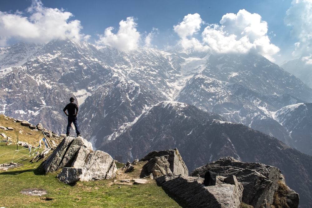 Un homme debout au sommet d’une montagne à côté d’un champ verdoyant