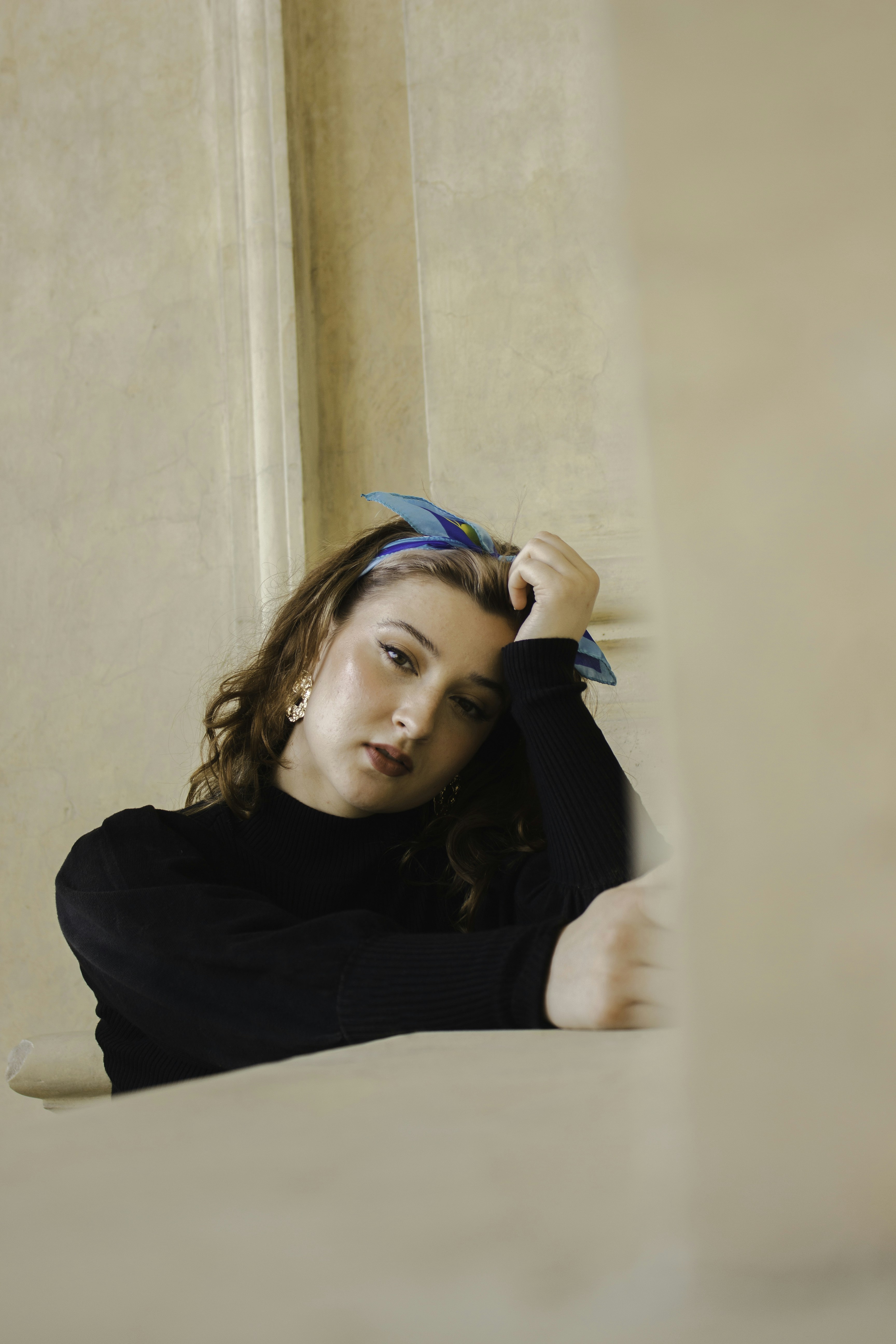 una donna appoggiata a un muro con la mano sulla testa