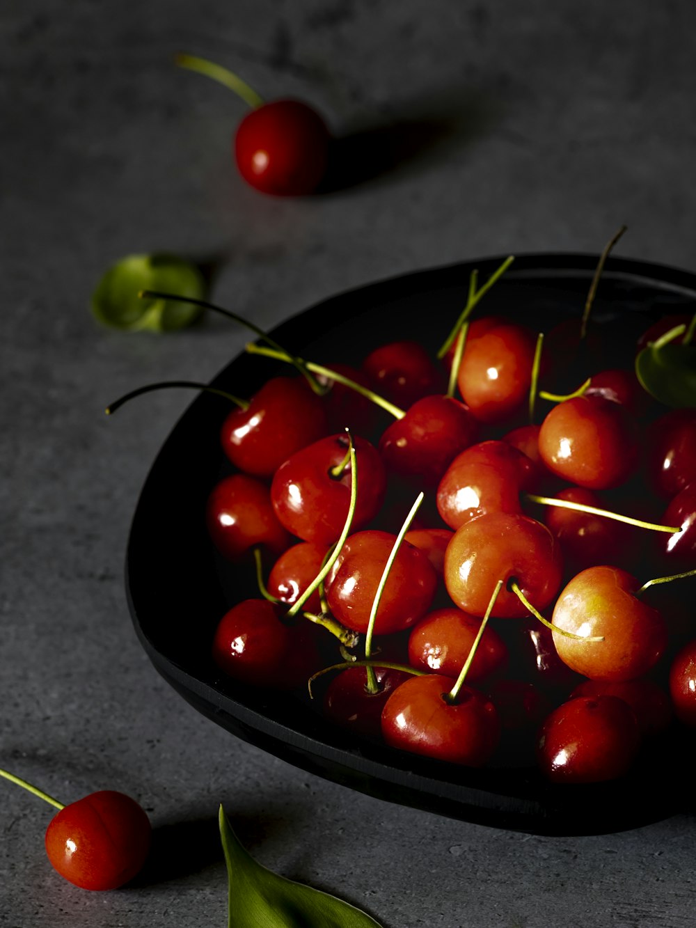 a bowl filled with cherries on top of a table