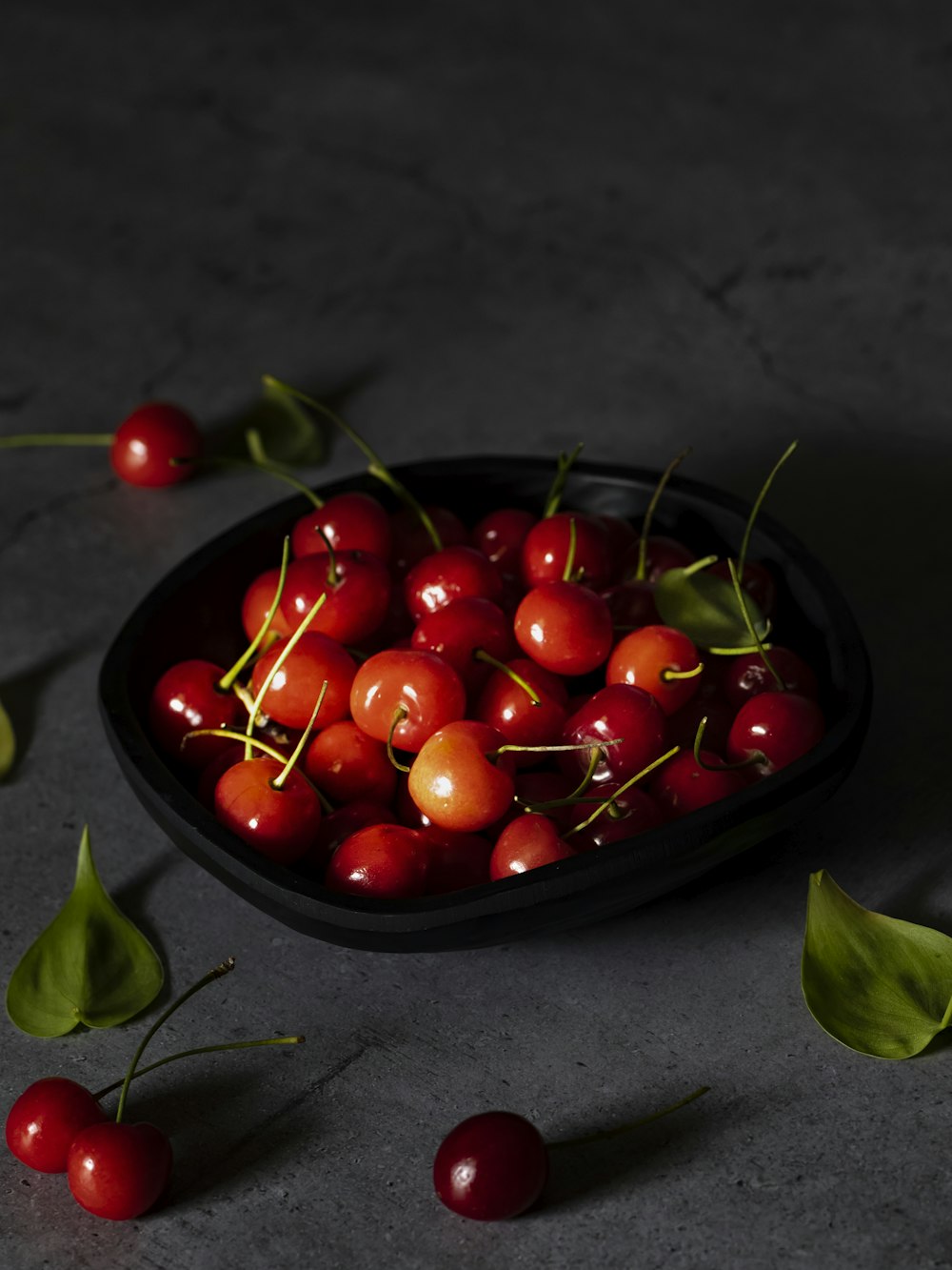 a bowl filled with cherries on top of a table
