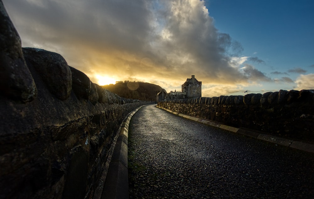 the sun is setting over a road with a castle in the background