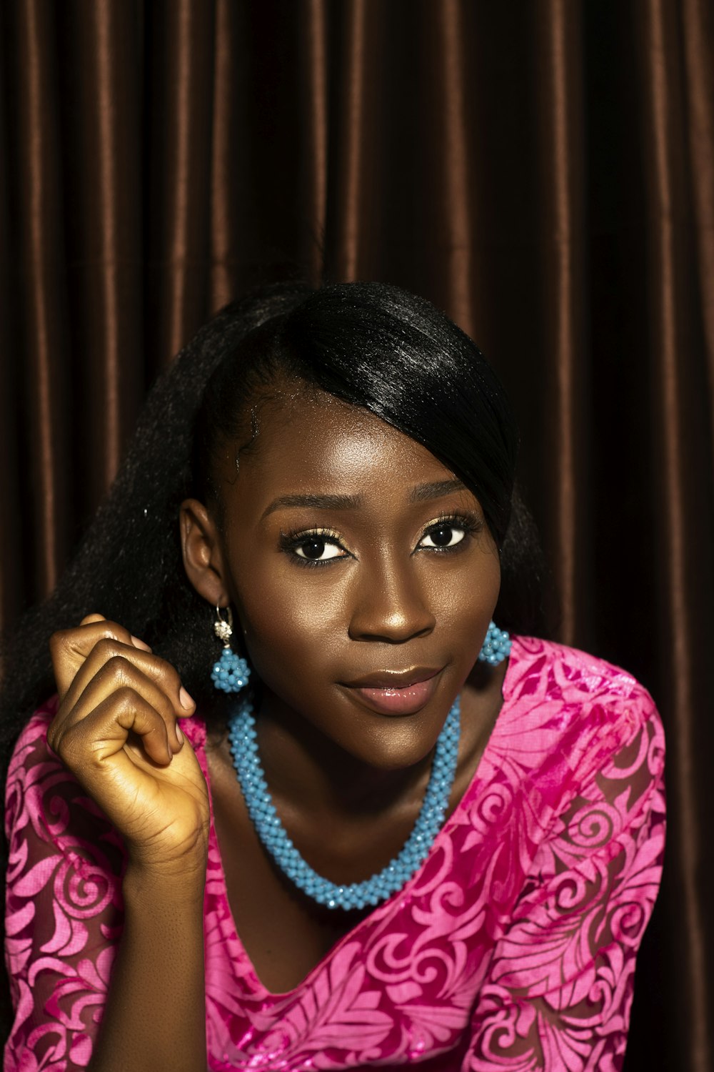 a woman in a pink dress with a blue beaded necklace