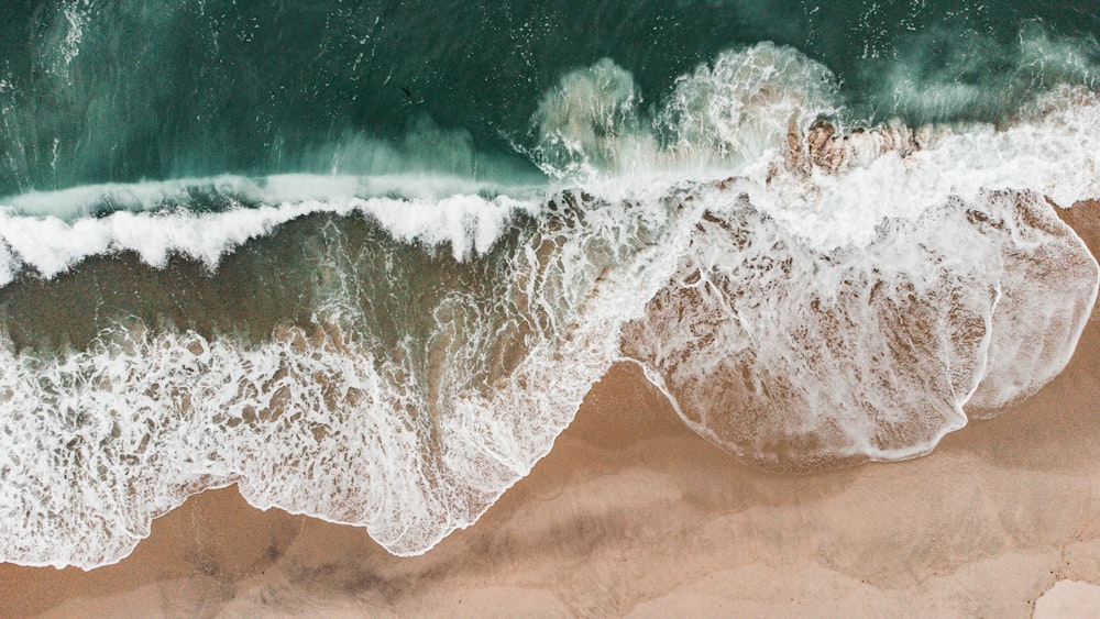 une vue aérienne d’une plage avec des vagues qui s’écrasent dessus