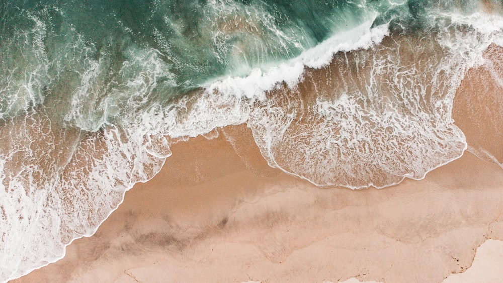une vue aérienne d’une plage avec des vagues qui s’écrasent dessus