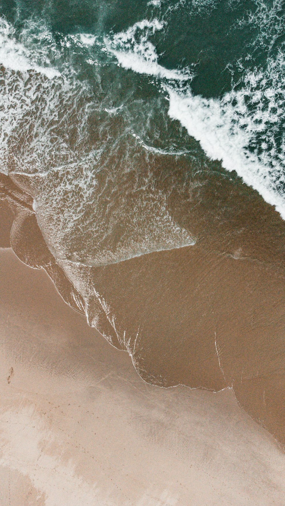 une vue aérienne d’une plage avec des vagues qui entrent
