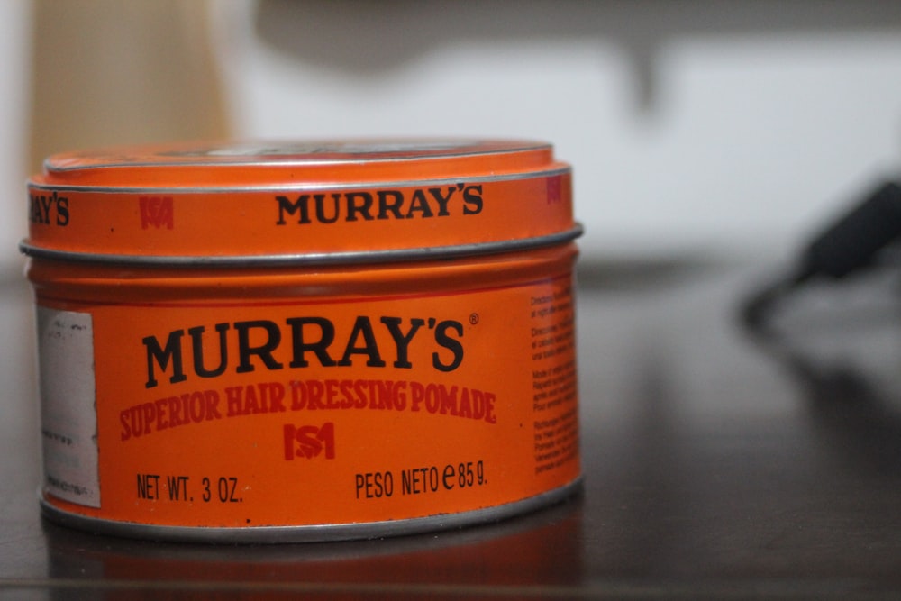 two tins of hair dressing sitting on a table