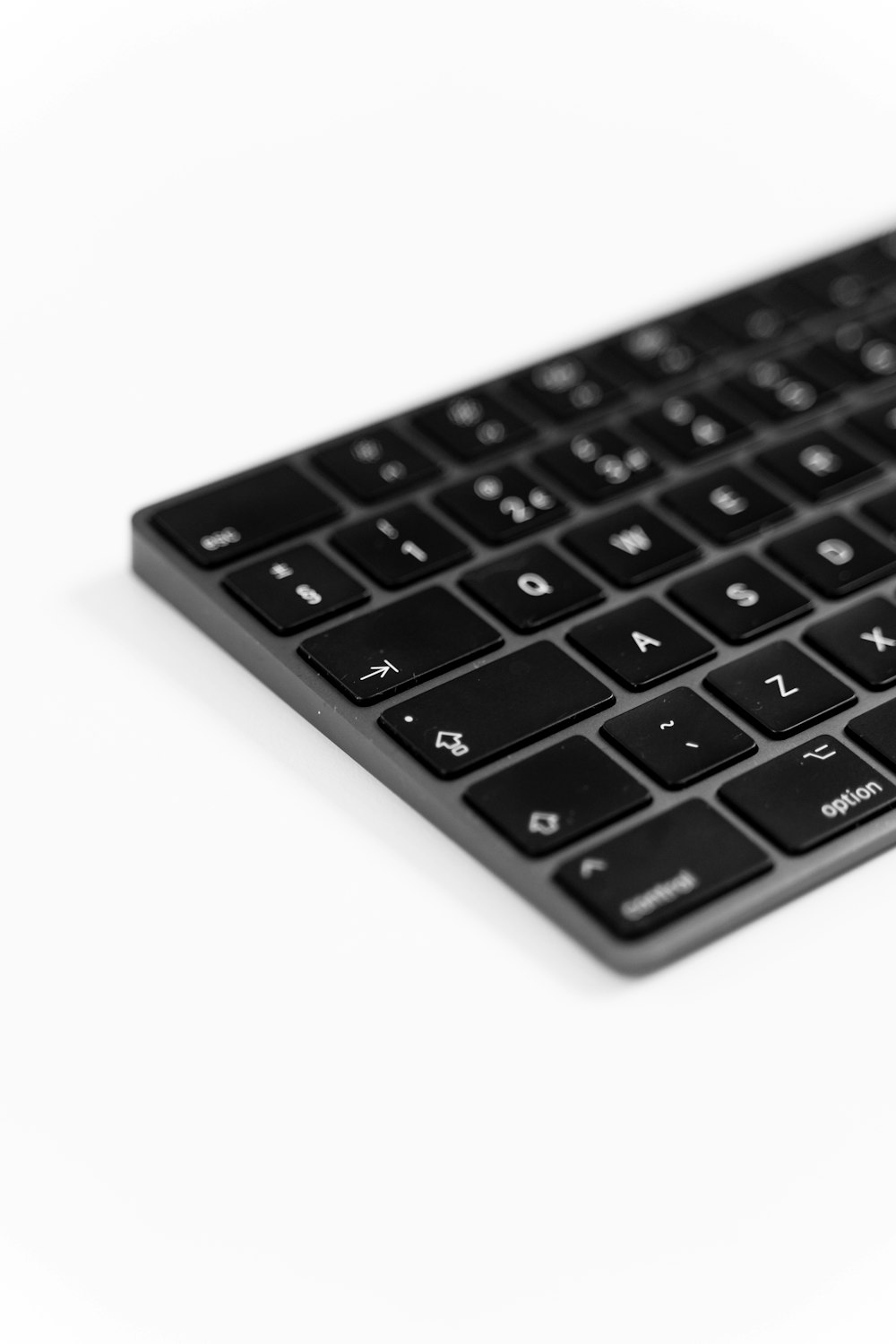 Un primer plano de un teclado negro sobre una superficie blanca