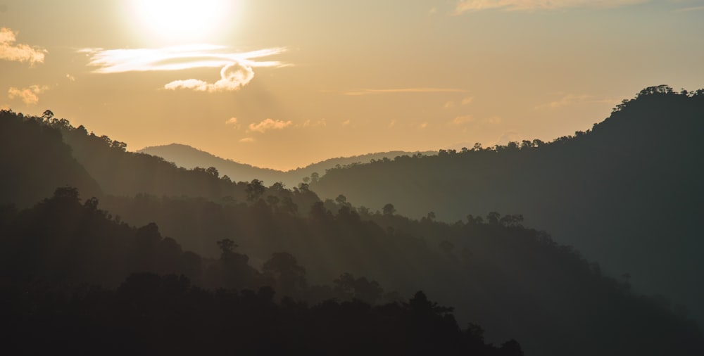 the sun is setting over a mountain range