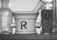 A black-and-white image featuring a mortar and pestle with the pharmacy symbol 'Rx' on its side. Flanking the mortar are two vintage glass bottles with embossed lettering, one with a label showcasing an old-fashioned portrait.