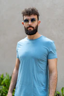a man with a beard wearing sunglasses and a blue shirt