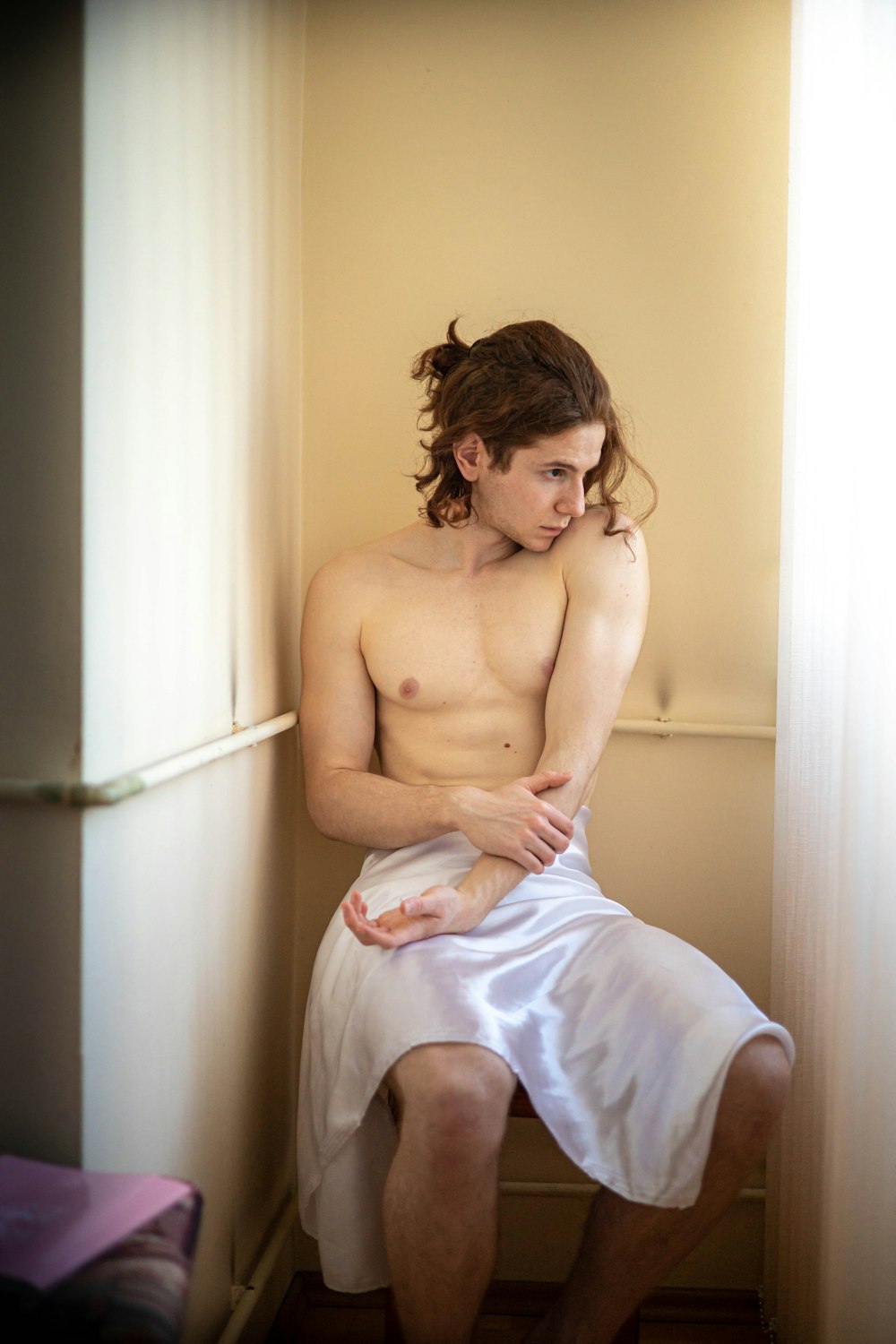 a shirtless man sitting on a toilet in a bathroom