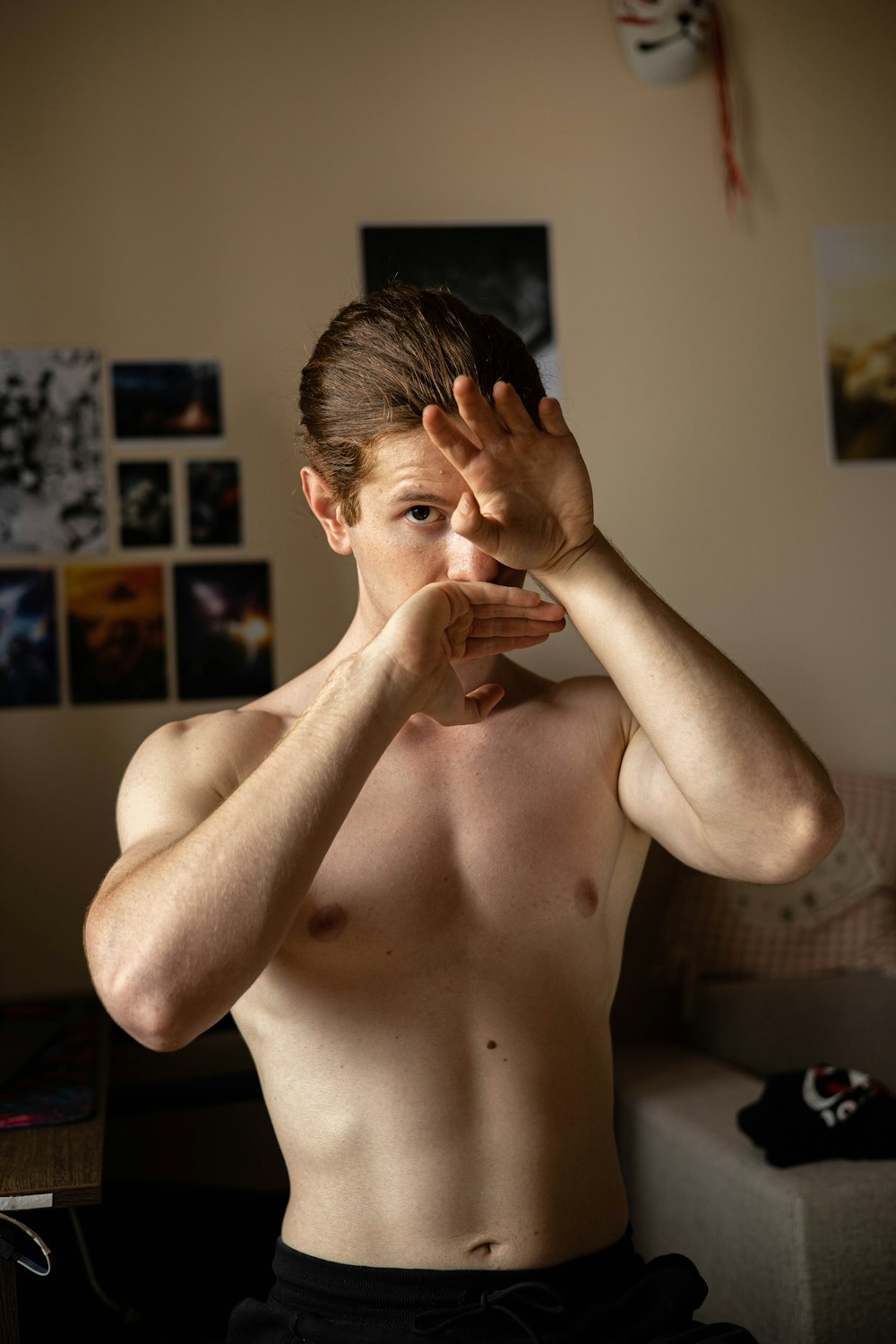 a shirtless man holding his hands up to his face