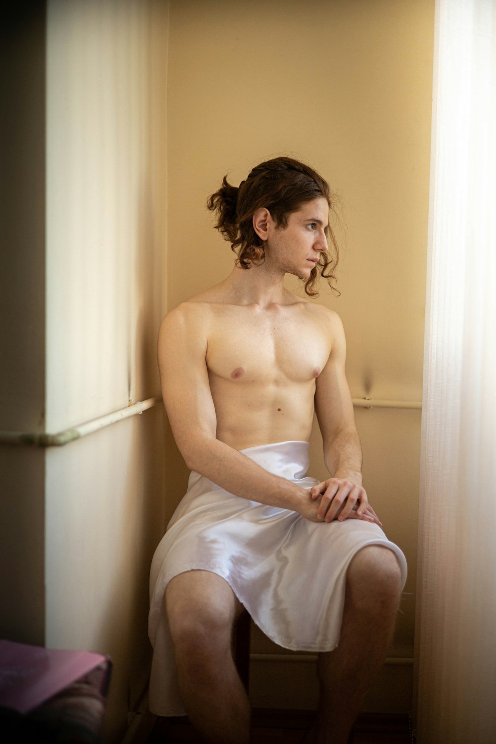 a shirtless man sitting on a toilet in a bathroom