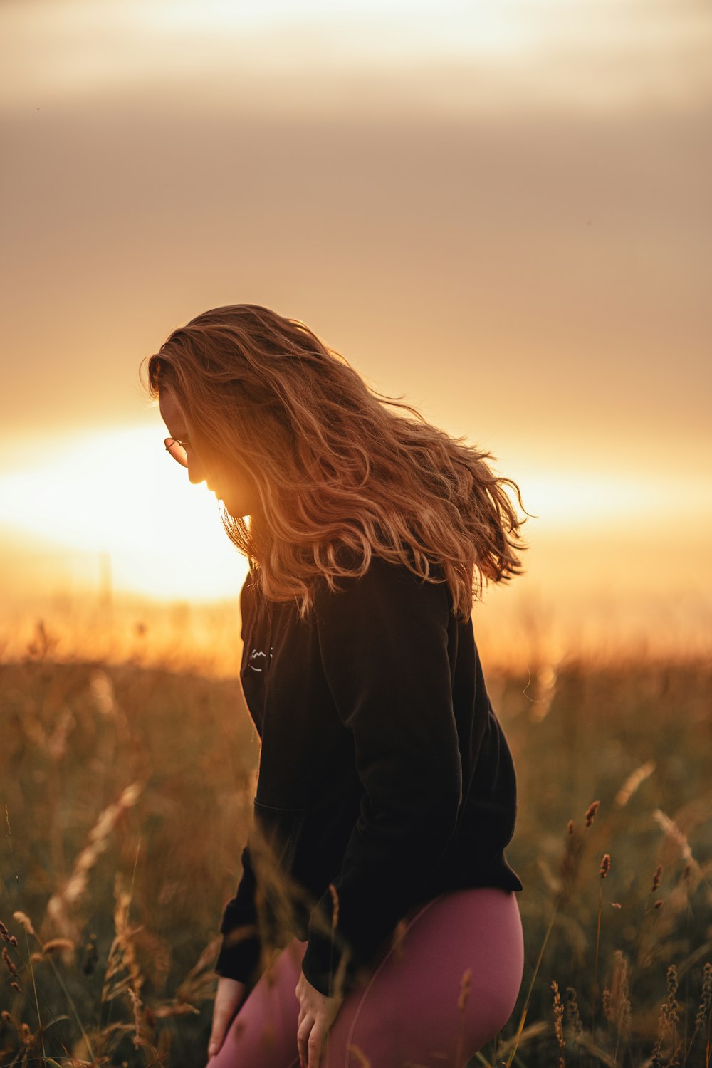 a woman kneeling down in a field of tall grass