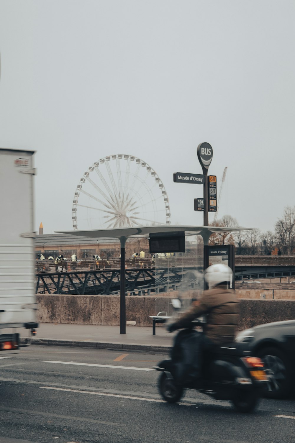 a man riding a motorcycle down a street next to a ferris wheel