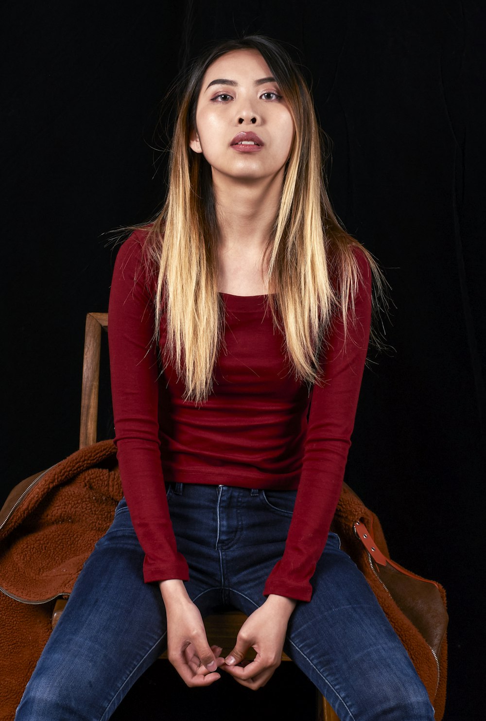 a woman sitting on a chair with her hands in her pockets