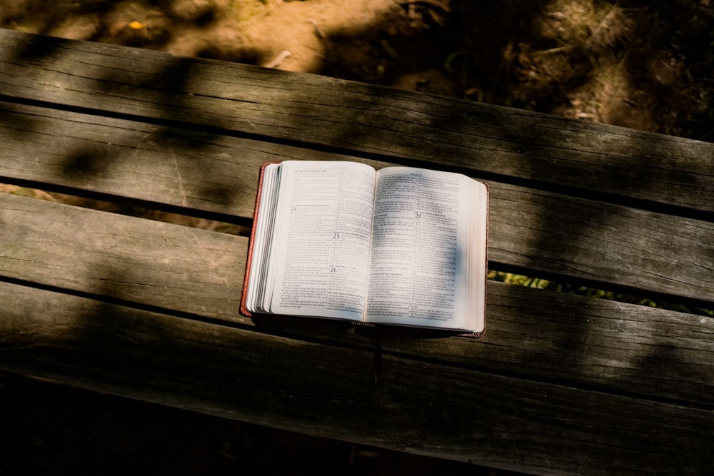 an open book sitting on top of a wooden bench