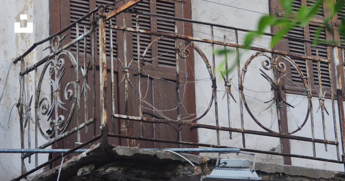 A balcony with a wrought iron railing and wooden shutters photo – Free ...