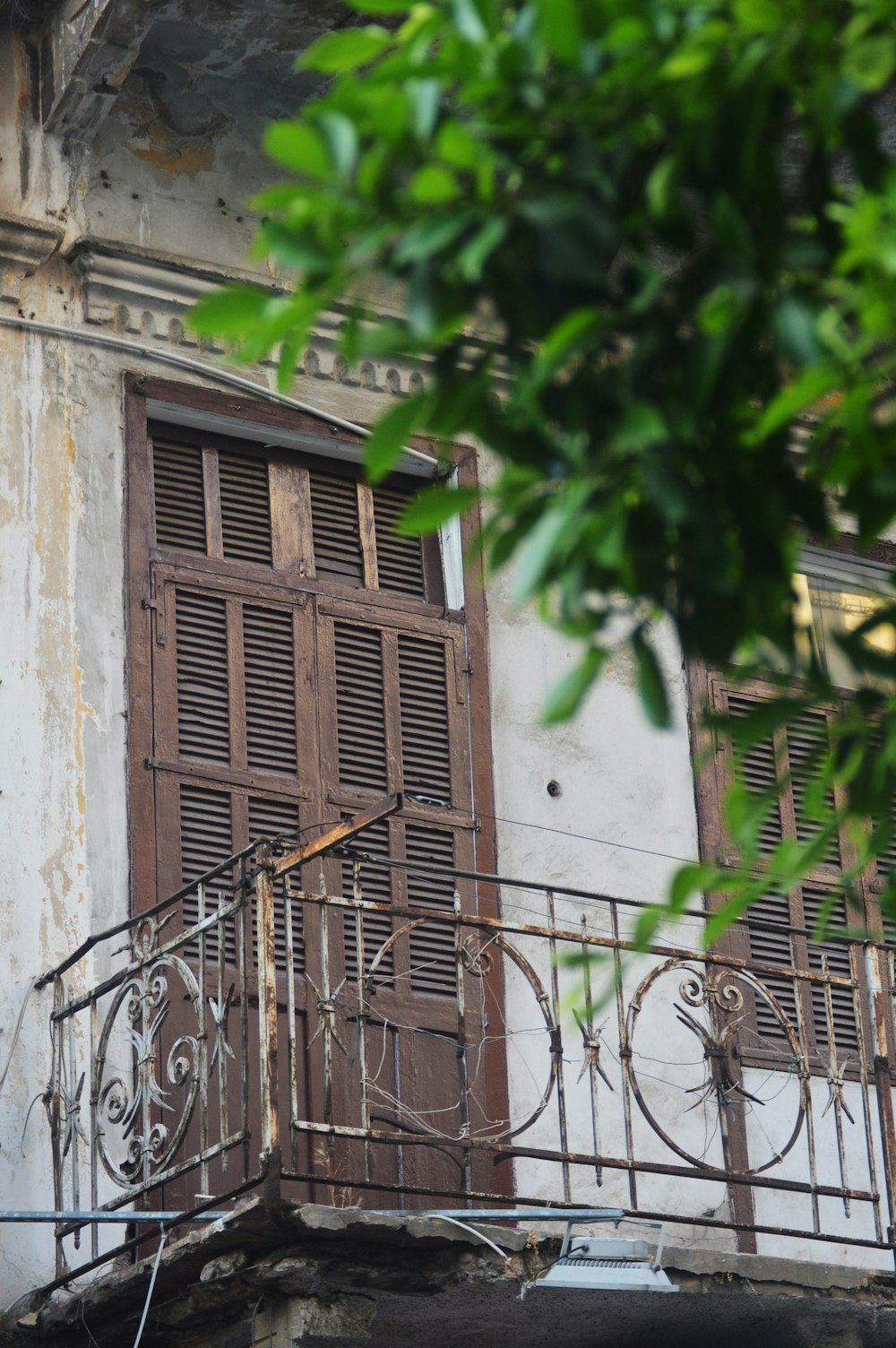 a balcony with a wrought iron railing and wooden shutters