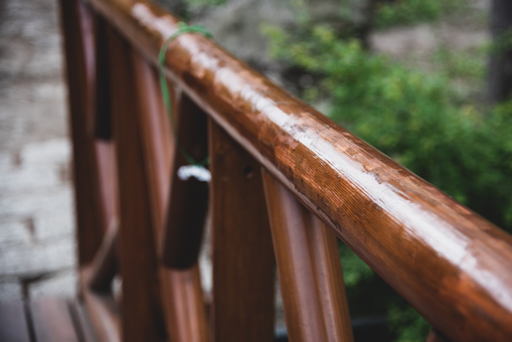 a close up of a wooden railing with a tree in the background