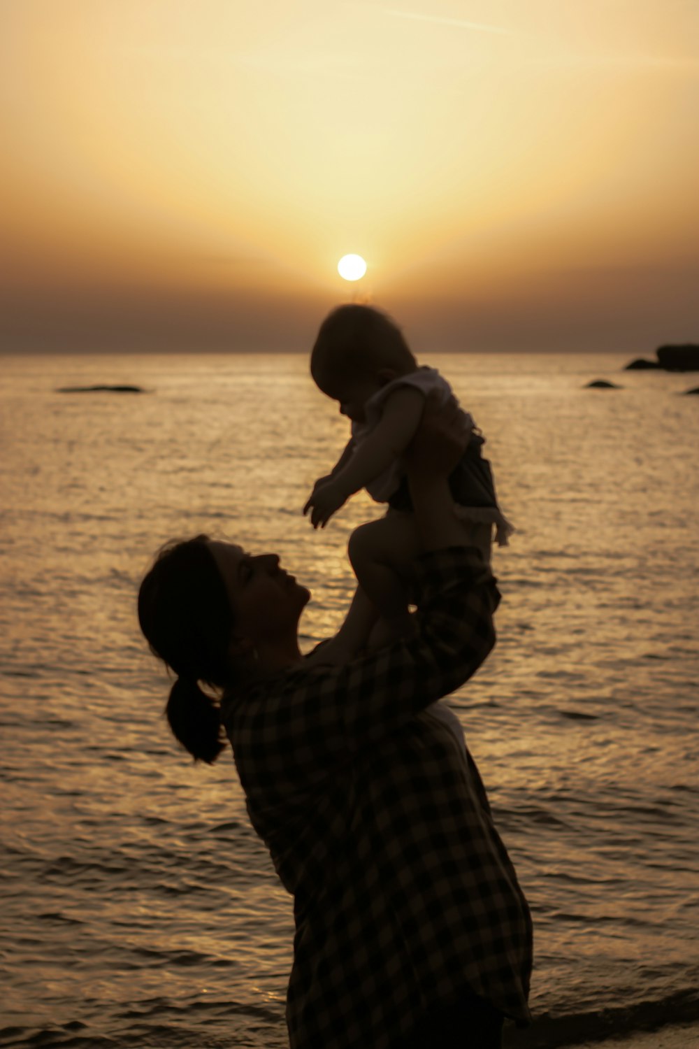a man holding a baby up to the sun
