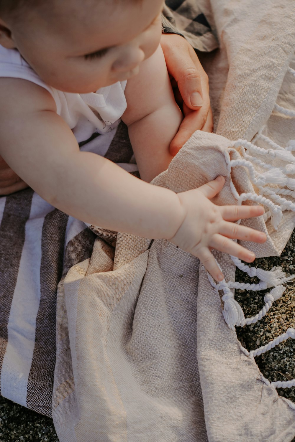 Un bébé joue avec une couverture par terre