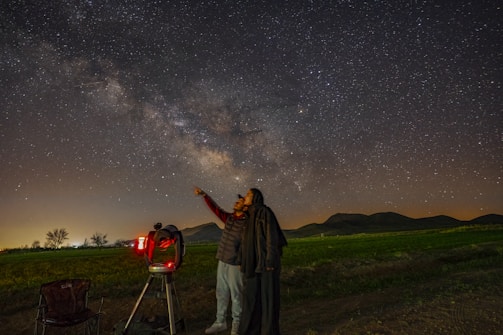 a man standing next to a telescope looking at the stars