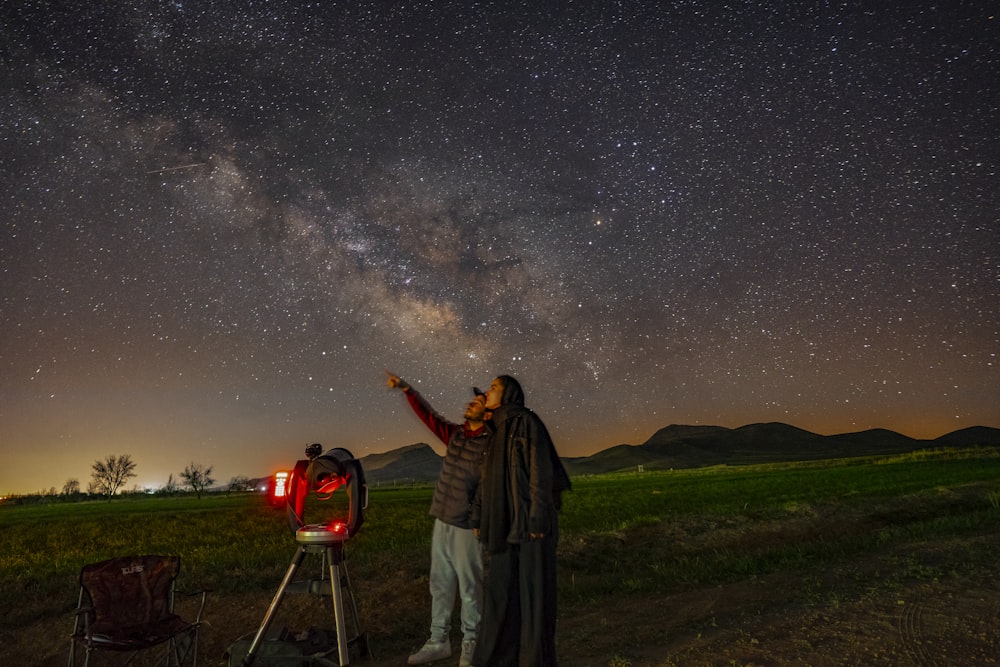 Ein Mann steht neben einem Teleskop und schaut auf die Sterne