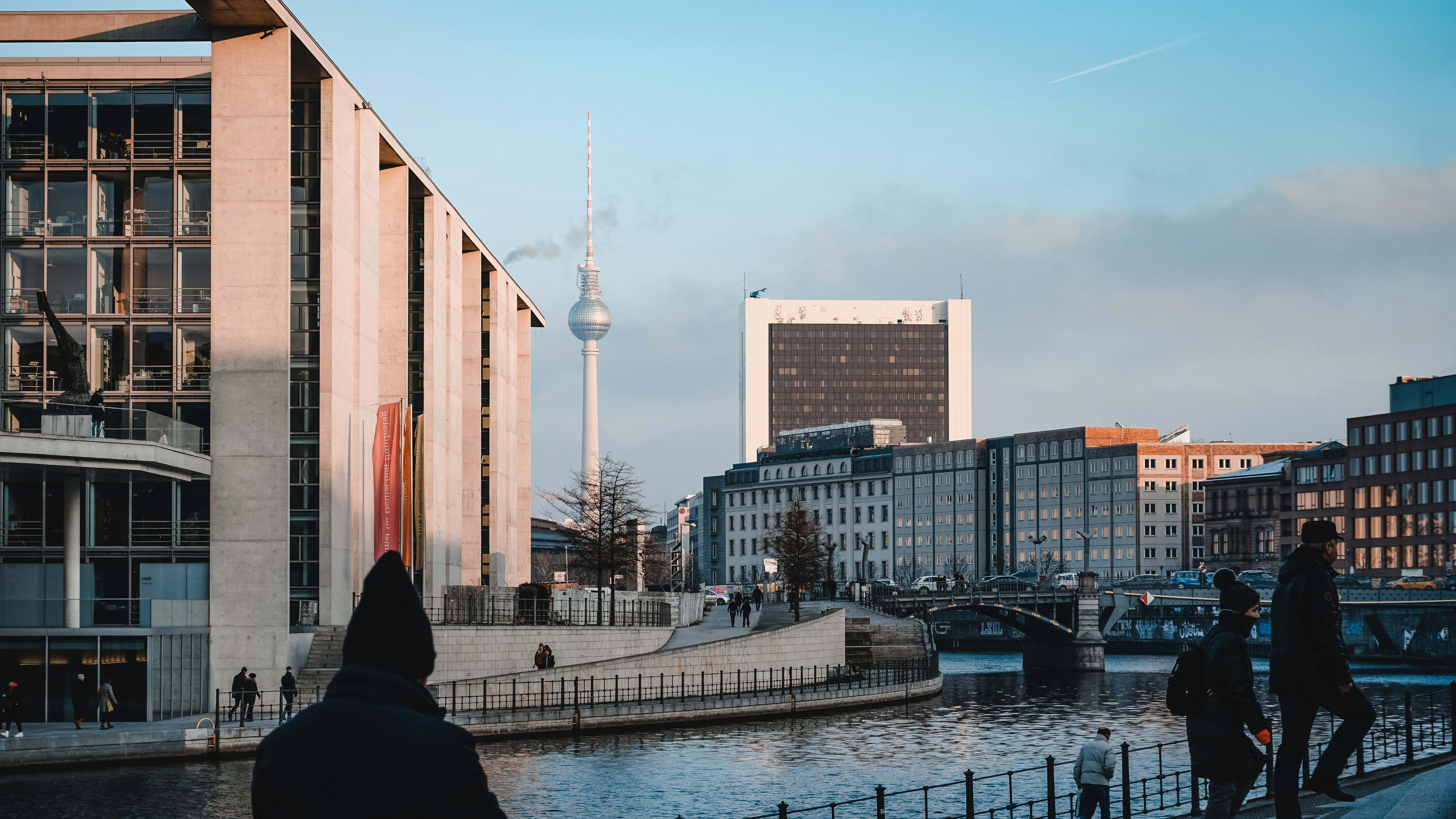 Eine Gruppe von Menschen, die entlang eines Flusses neben hohen Gebäuden spazieren gehen