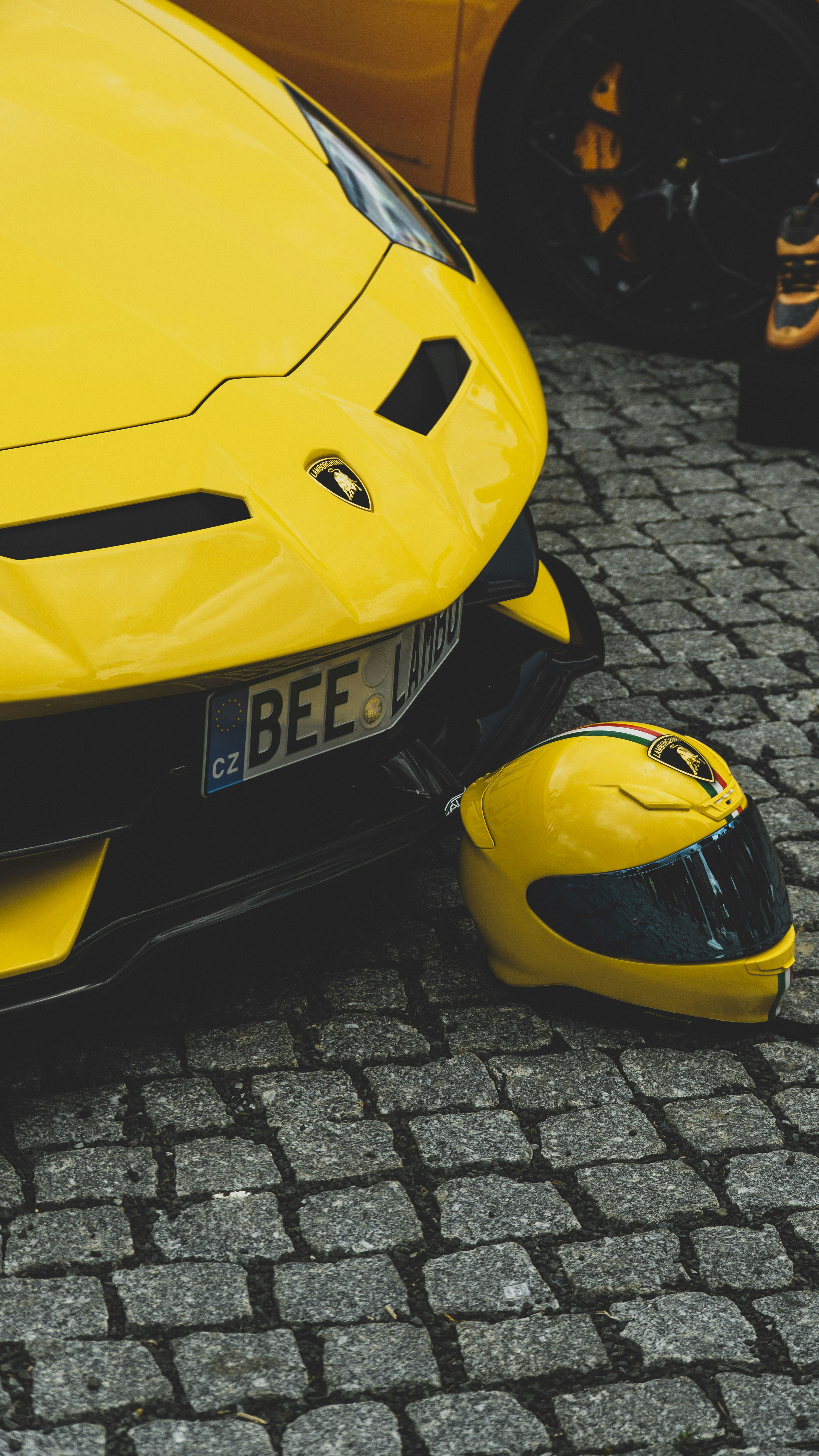 a close up of a yellow sports car with a mouse on the ground