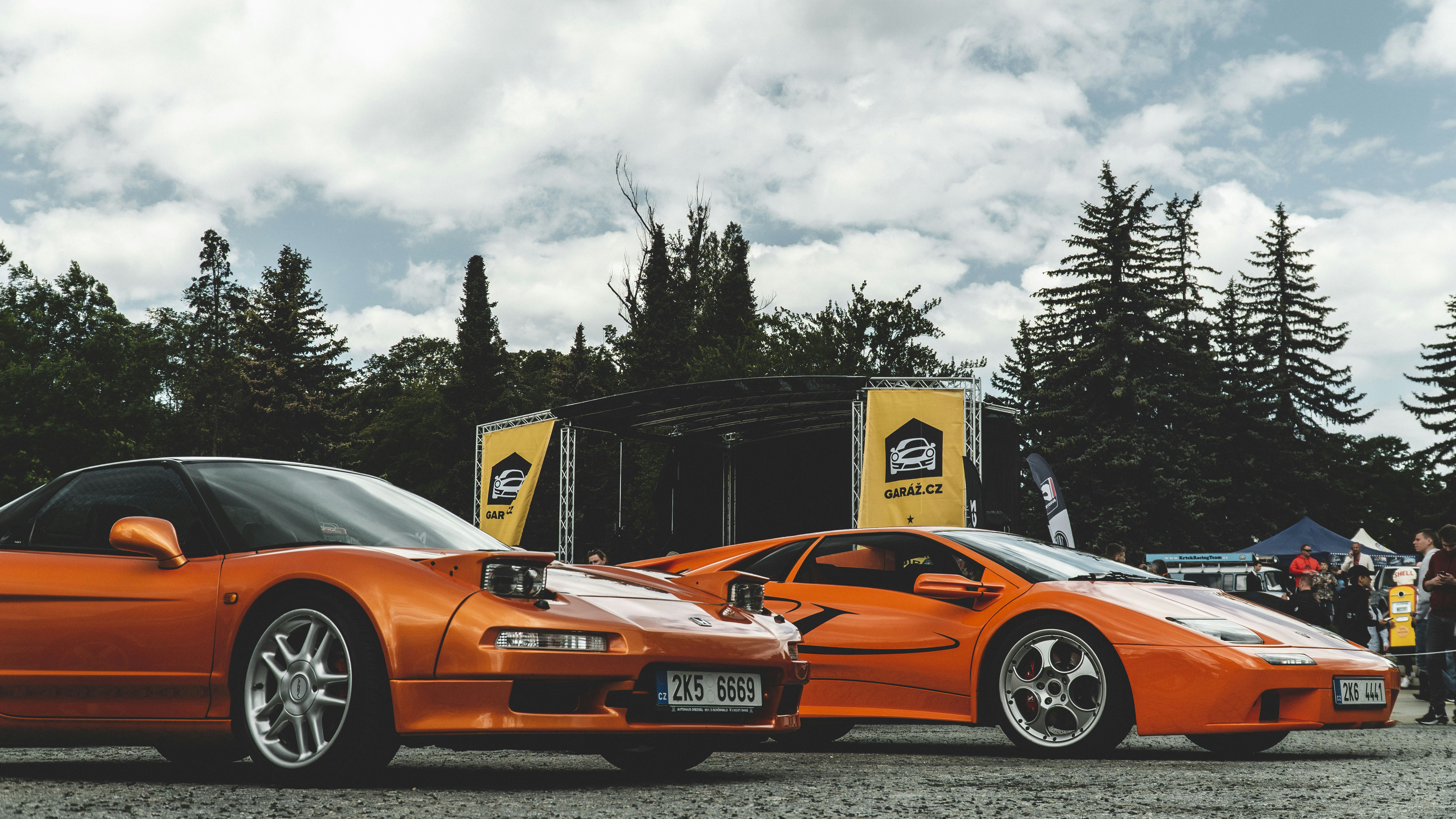 two orange sports cars parked next to each other