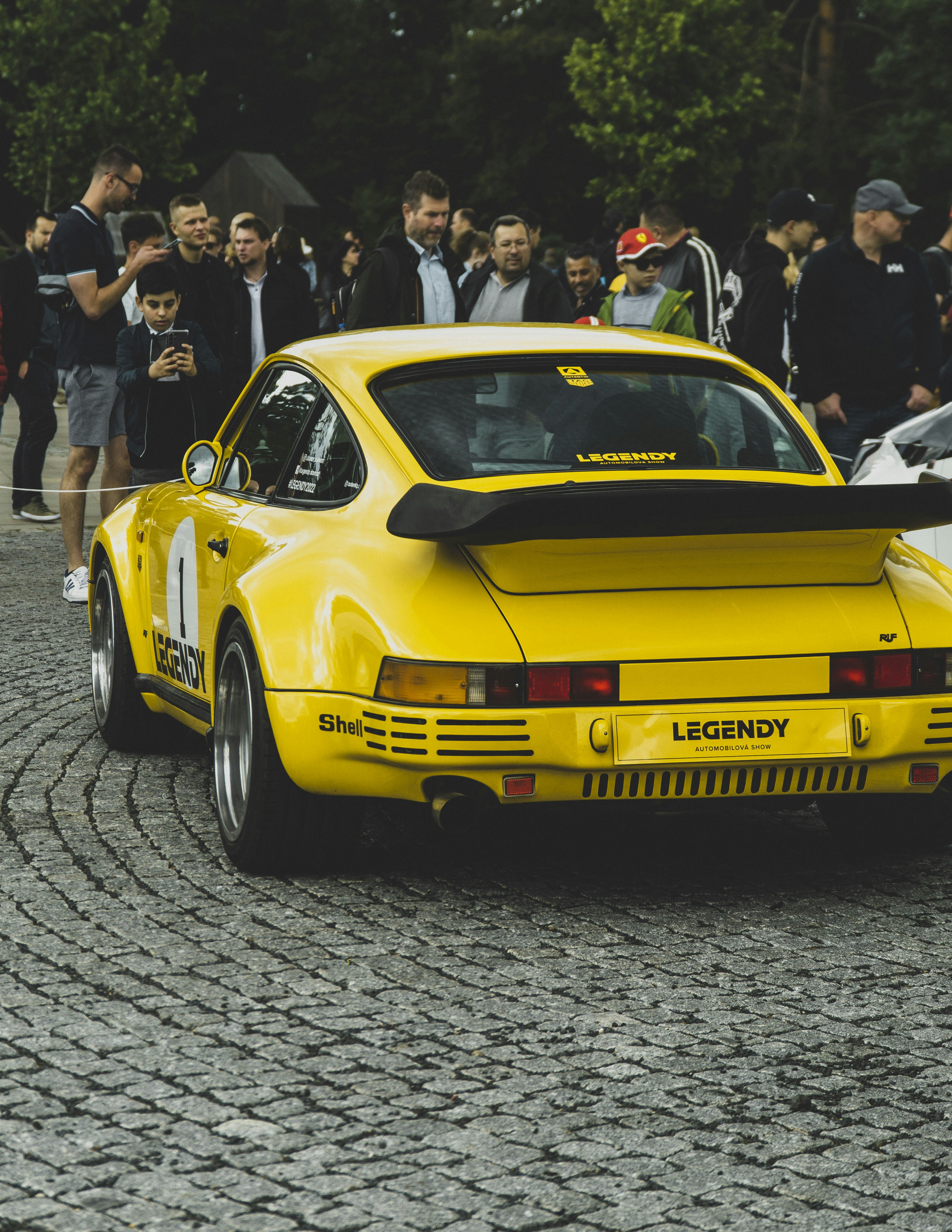 a yellow sports car driving down a cobblestone road