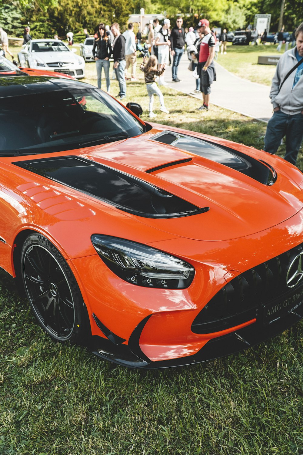 an orange sports car parked on top of a lush green field