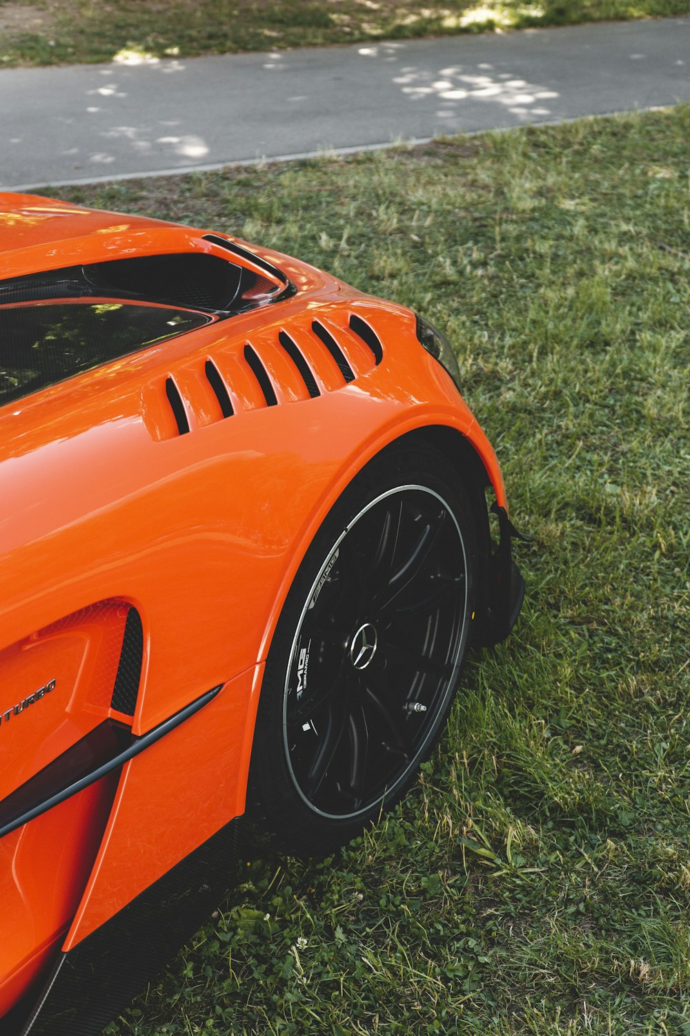 an orange sports car parked in the grass