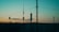 Several antennas and communication equipment are silhouetted against a gradient sky. The sky transitions from blue at the top to a warm orange and yellow near the horizon, suggesting either sunrise or sunset. The scene conveys an industrial setting with a focus on telecommunications.