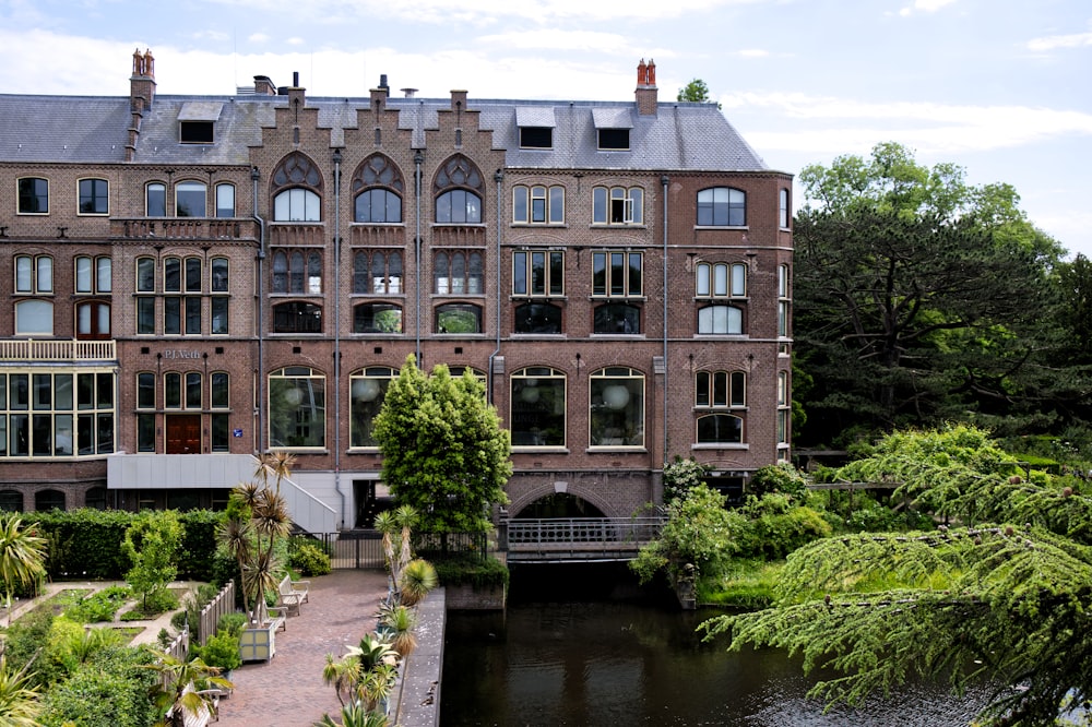 a large brick building with many windows next to a river