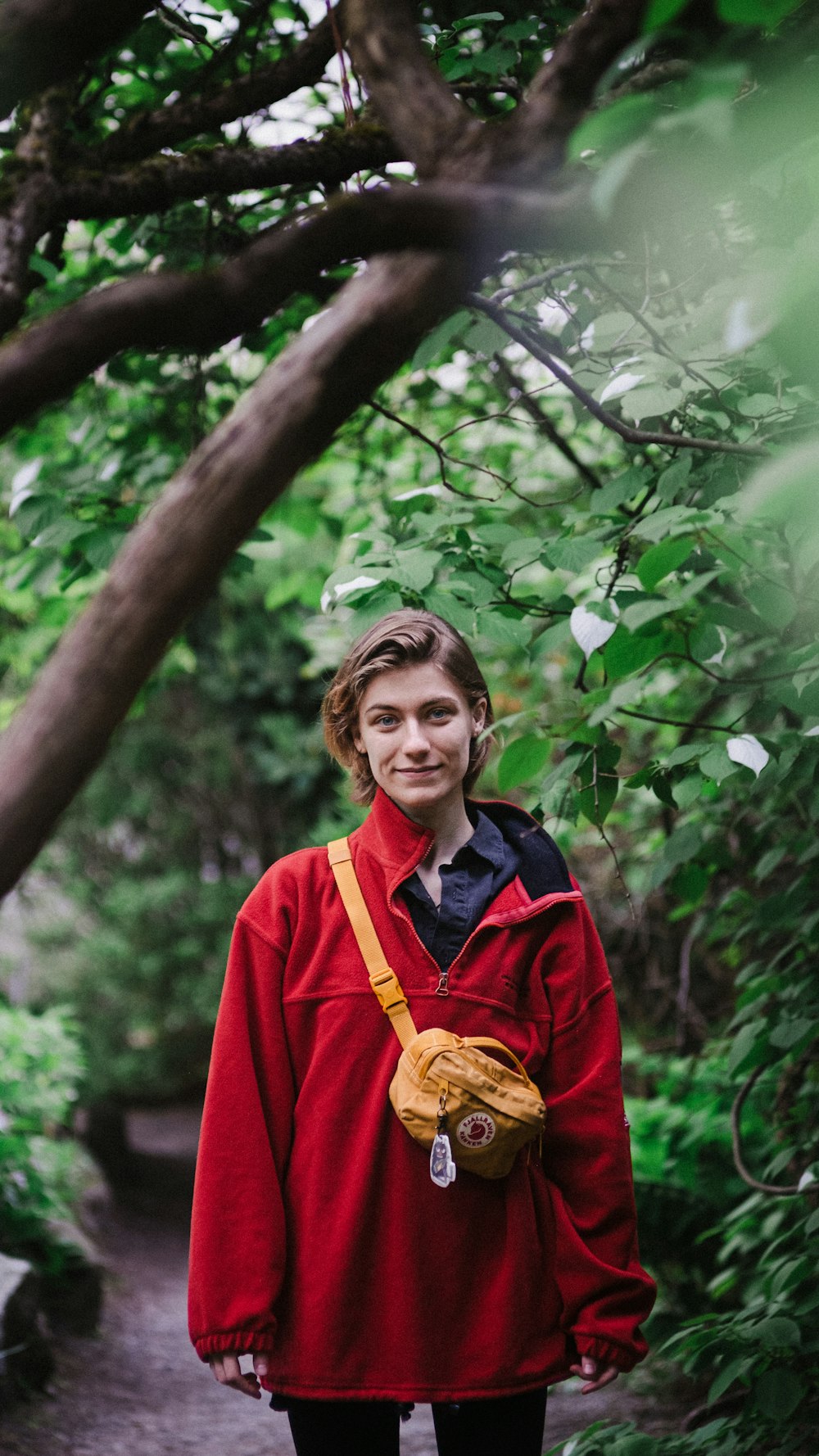 a man in a red jacket is standing in the woods