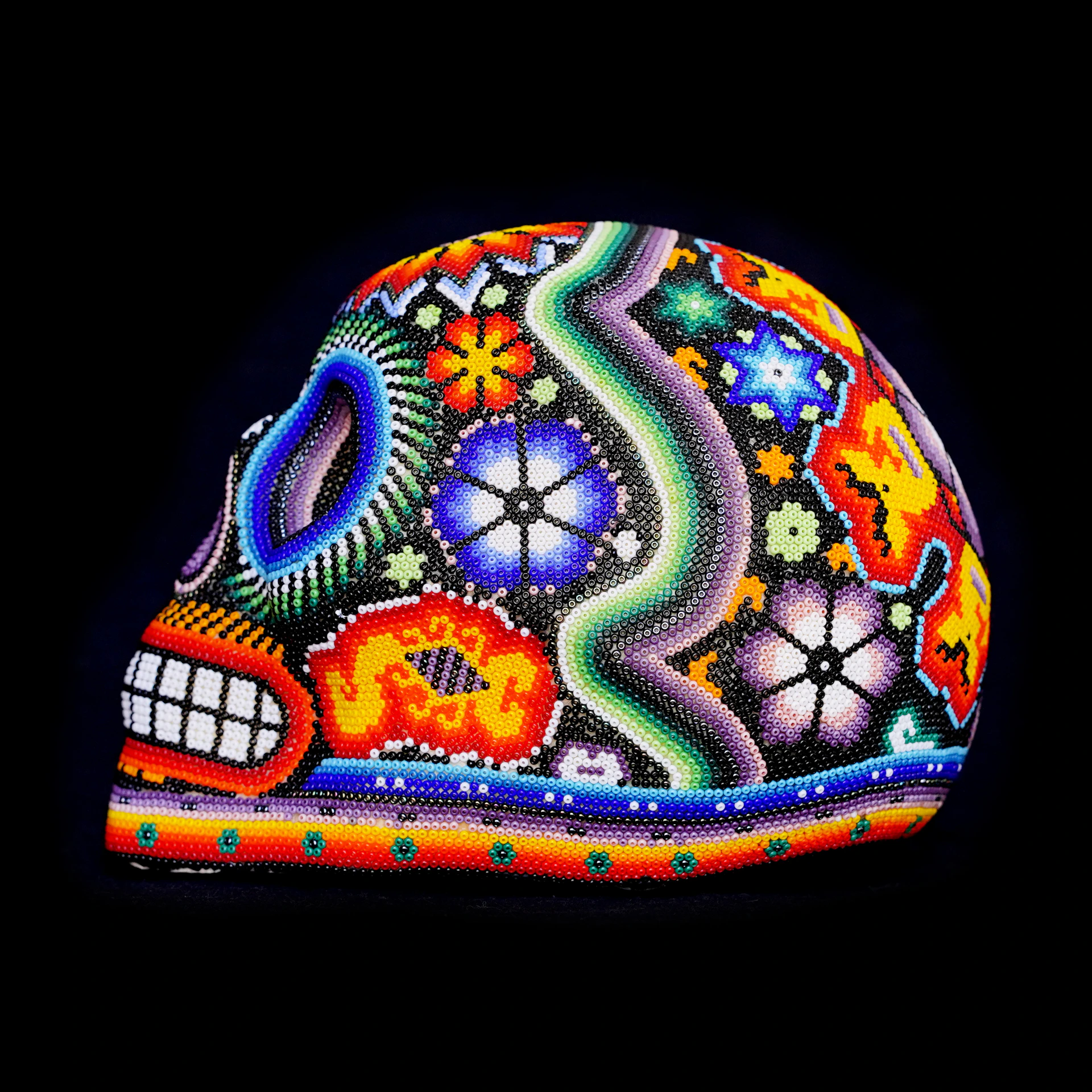a colorful skull made of beads on a black background