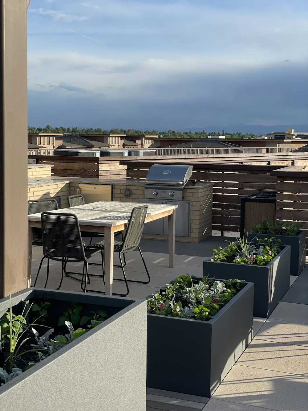 a table and chairs on a roof with a grill in the background