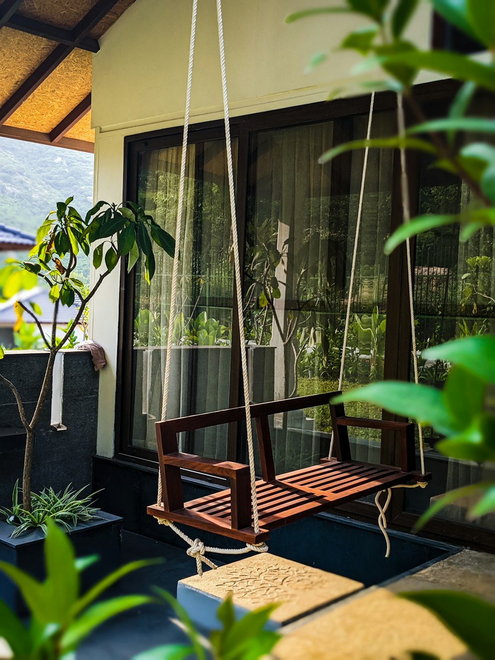 une balançoire en bois assise à côté d’une fenêtre