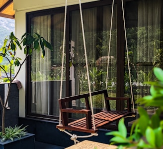 a wooden swing hanging from the side of a house