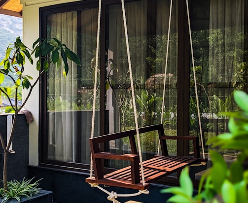 a wooden swing hanging from the side of a house