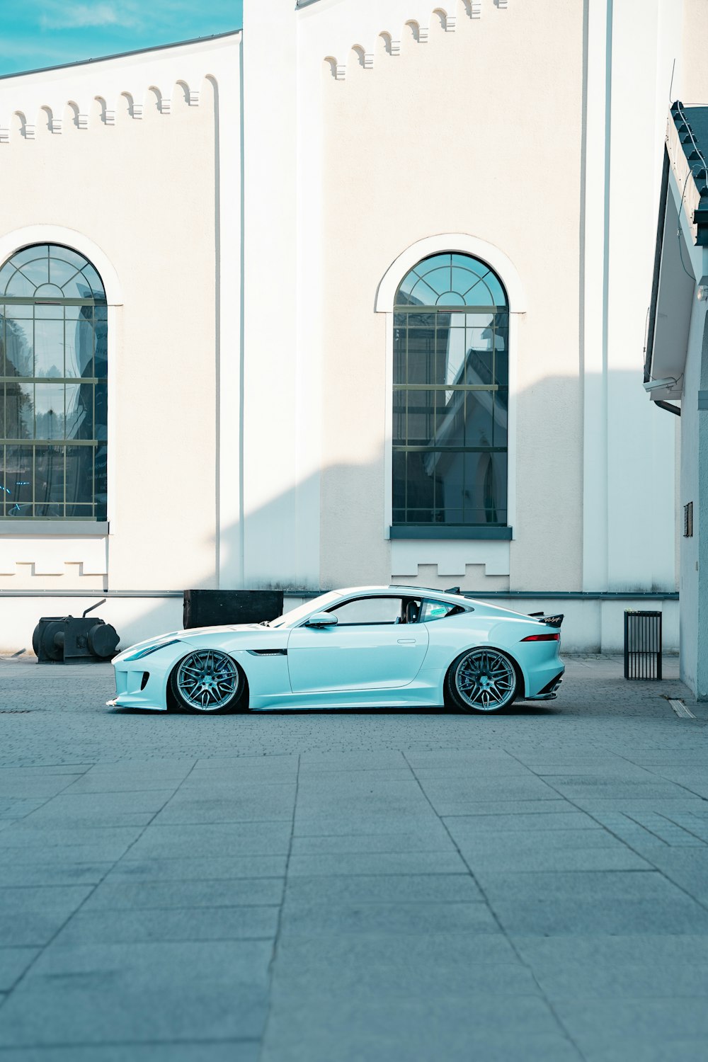 a blue sports car parked in front of a white building