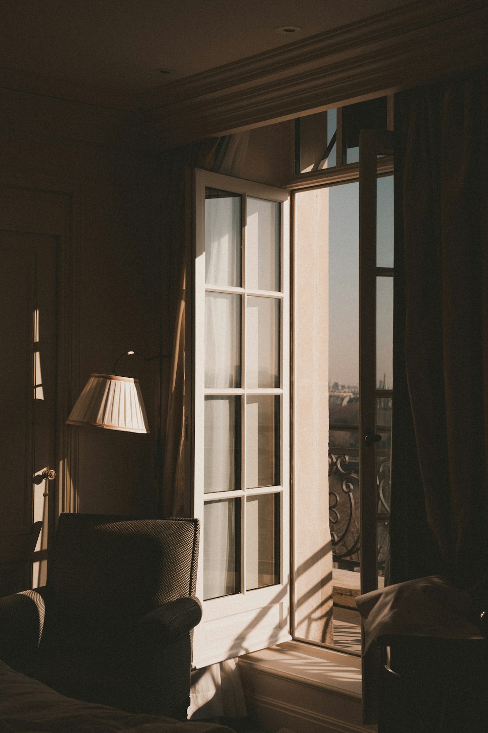 a chair sitting in front of a window next to a lamp