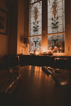 Dimly lit dining room with flickering candles and ghostly silhouettes on dark purple walls.