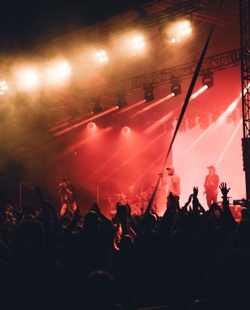 A vibrant photo of wunmi performing live on stage, bathed in warm spotlight with an enthusiastic crowd in the background.