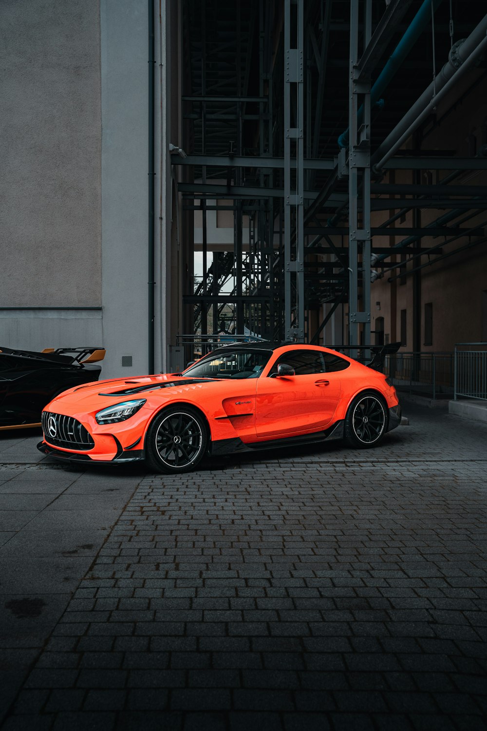 an orange sports car parked in front of a building