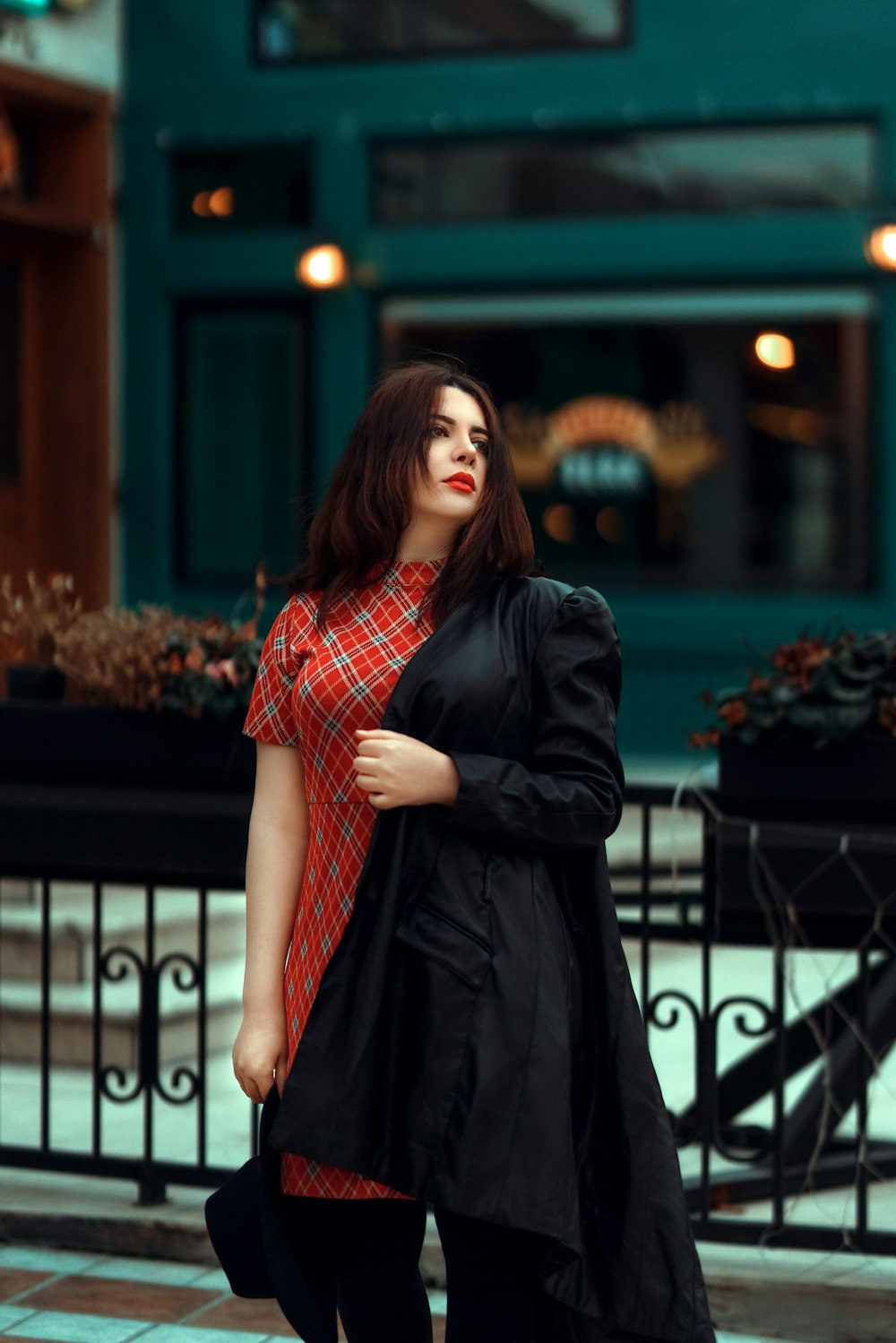 a woman walking down a street next to a fence