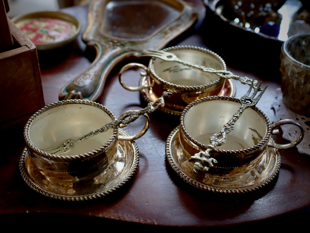 a table topped with silver cups and saucers