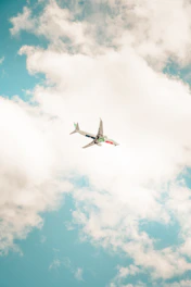 Colorful illustration of a cartoon airplane soaring through a bright blue sky with fluffy clouds.